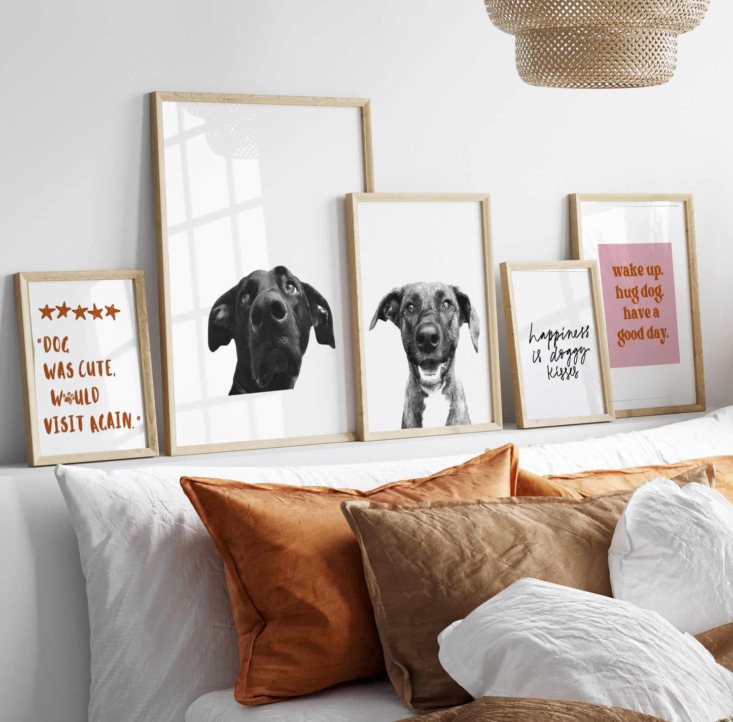 A set of three picture frames with white mats and clear glass, displaying black and white dog illustrations with accompanying text, placed on a white wall above a sofa with orange cushions.