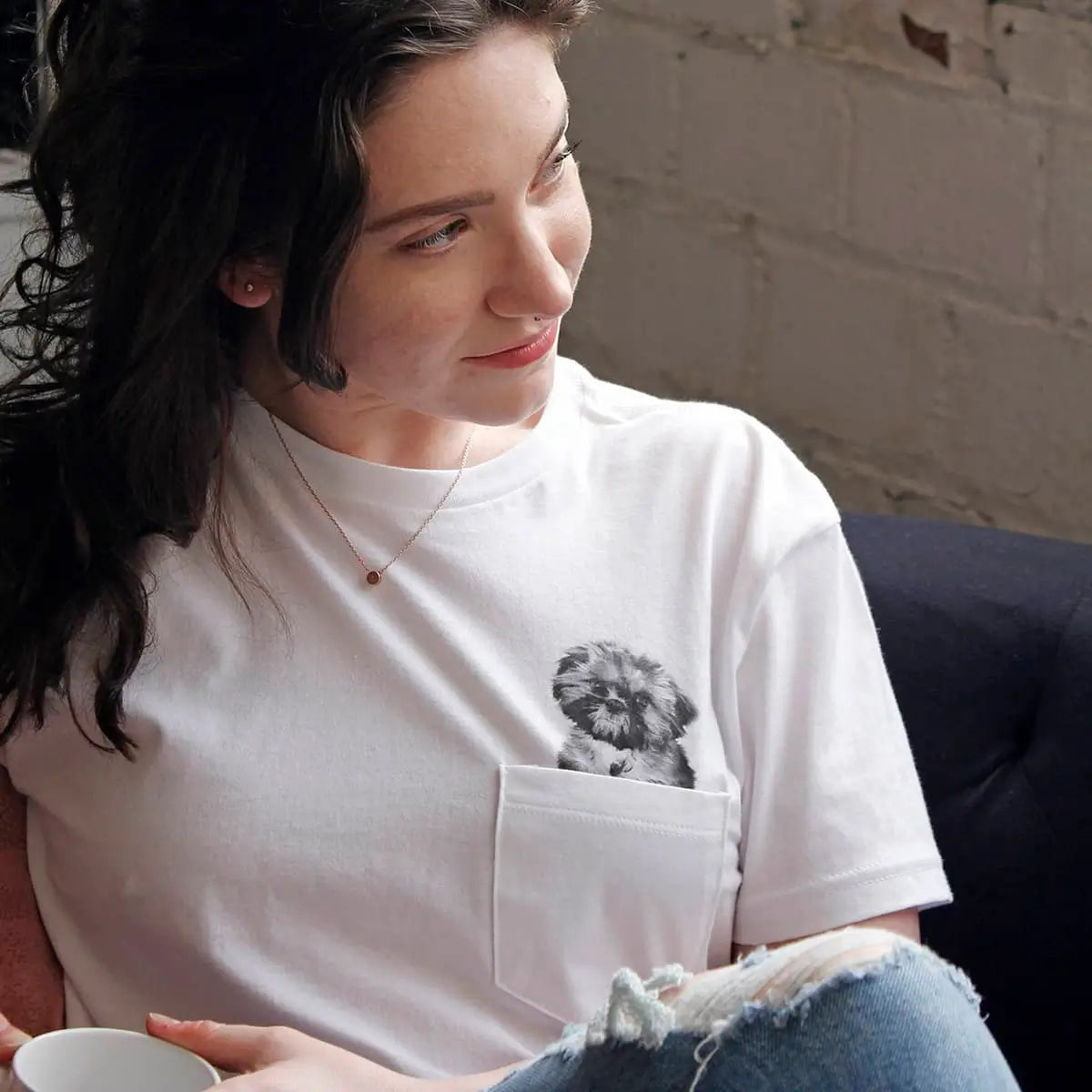 Woman wearing a white t-shirt with a graphic design, sitting indoors.