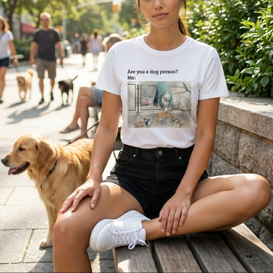 Woman sitting on a bench with a dog, wearing a t-shirt with a graphic and text.
