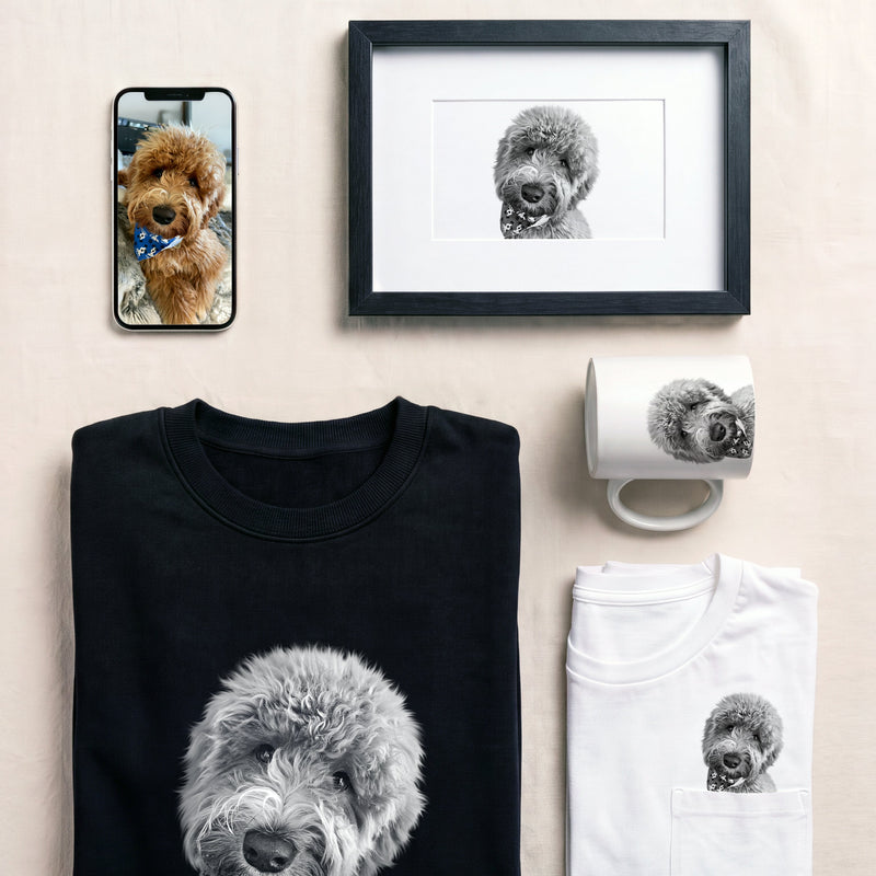 A flat-lay product presentation featuring a black crewneck t-shirt and a white t-shirt, both printed with a gray and white doodle dog graphic. A matching white mug is shown on the right, and a framed print of the dog's face is shown at the top.