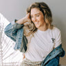 Woman wearing a white t-shirt and denim jacket indoors