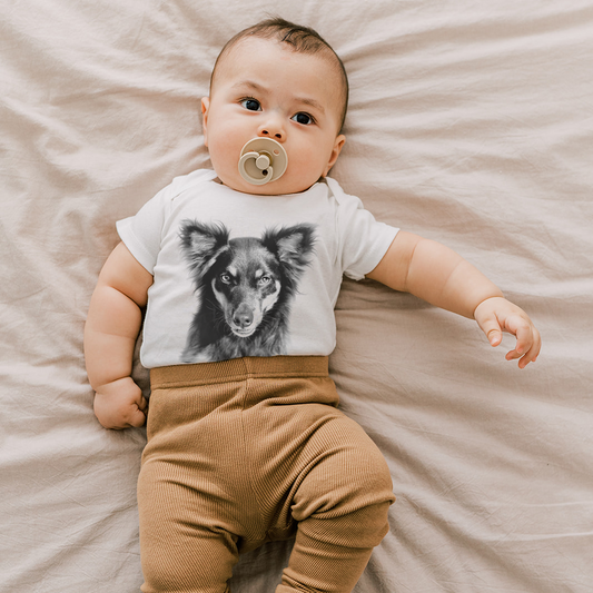 Baby wearing a onesie with a dog graphic on a beige blanket