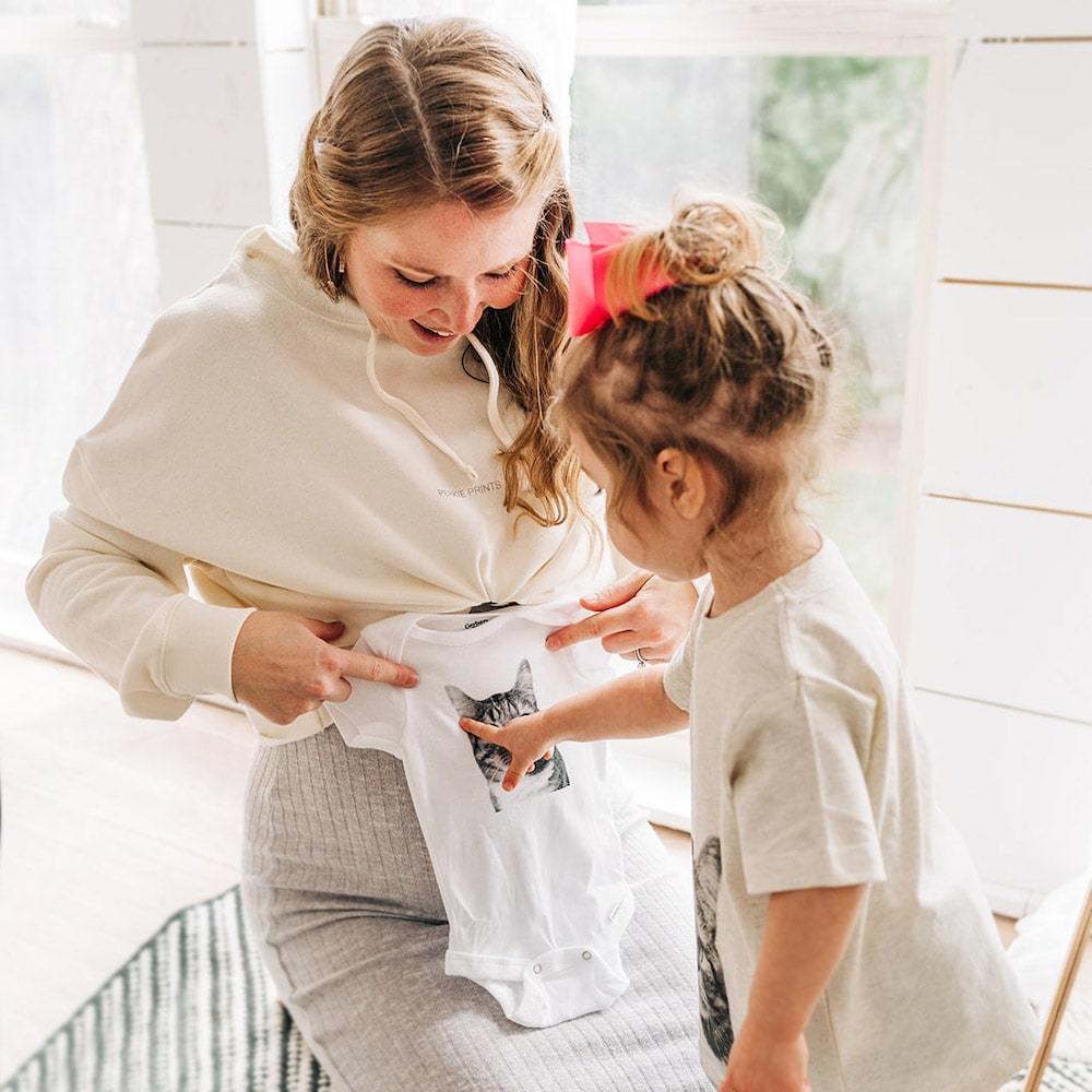 expectant mother receives gift of custom baby onesie with cat picture